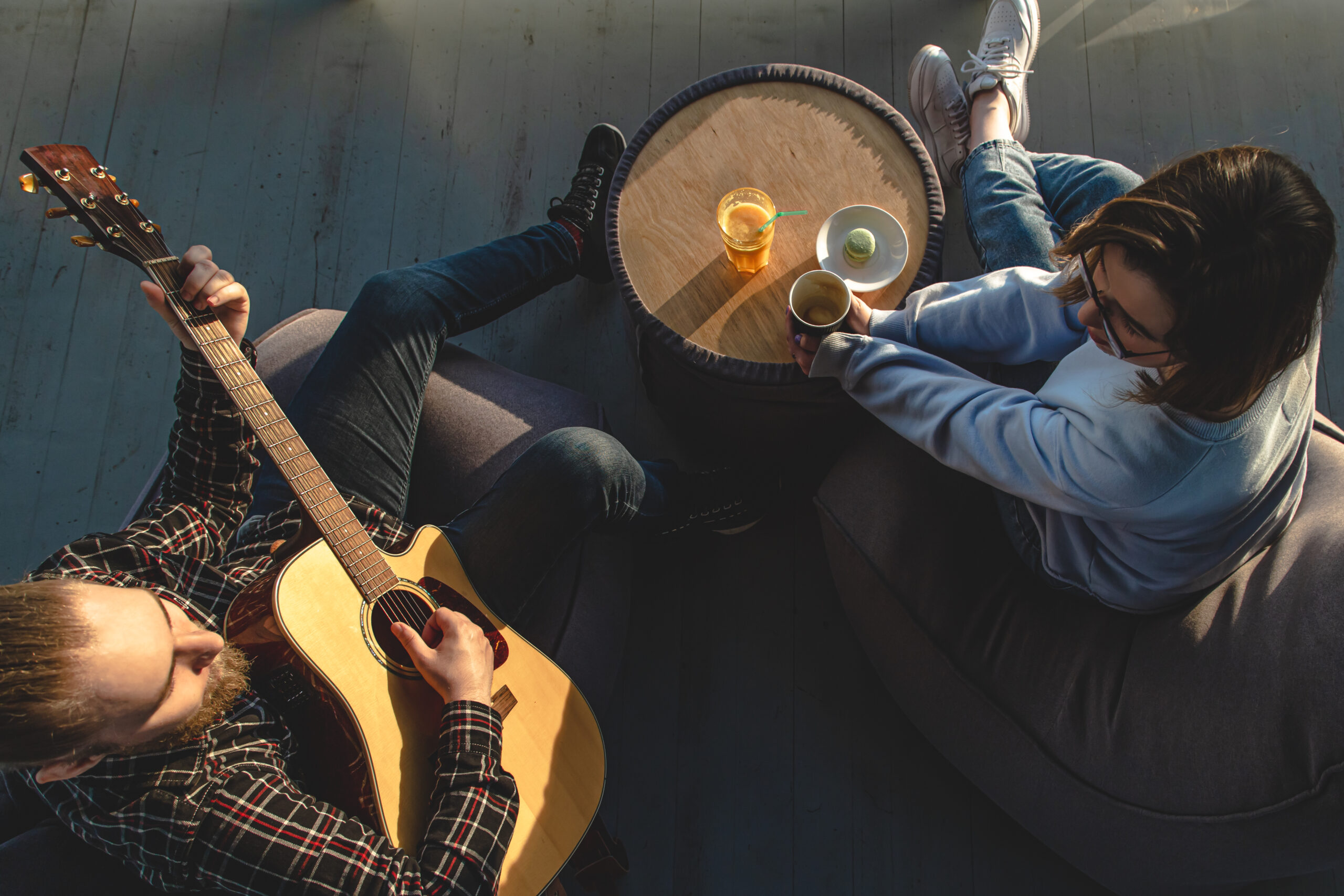 A young man plays the guitar for a girl, top view. zene terápia